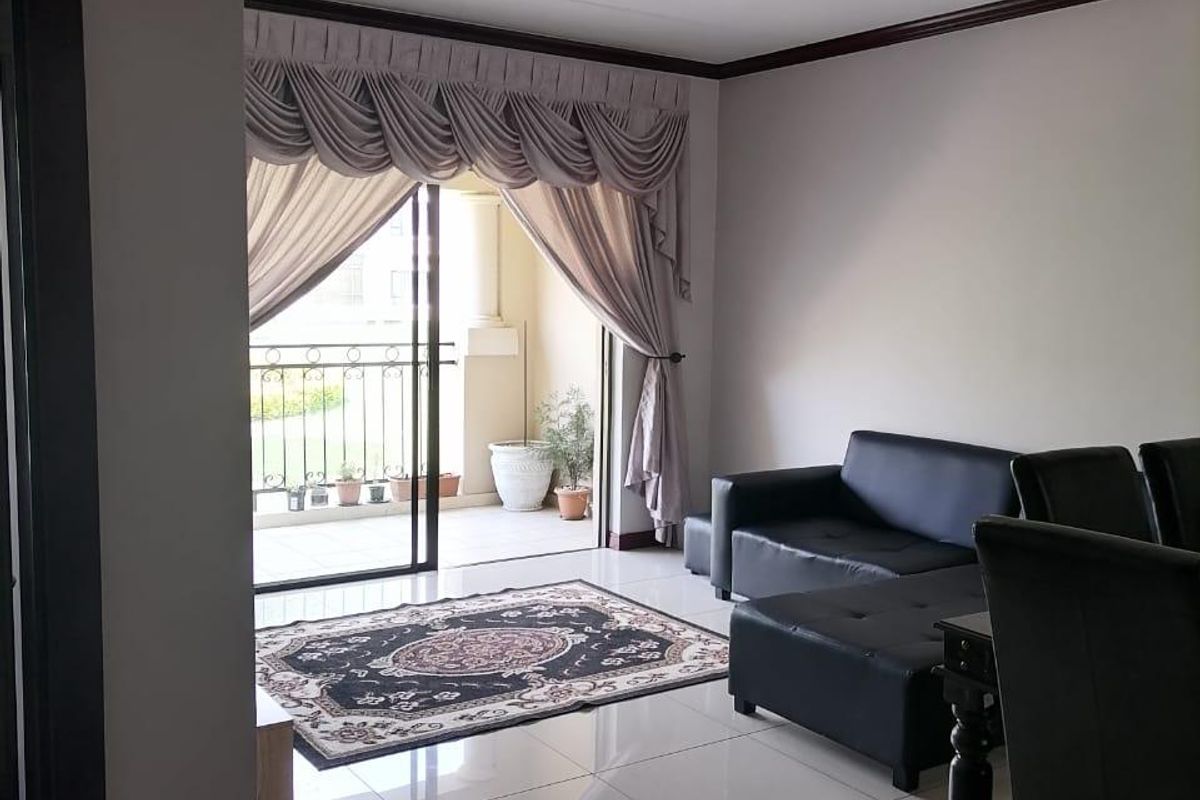 A bright living room featuring tiled flooring and direct access to a private balcony through a sliding glass door.
