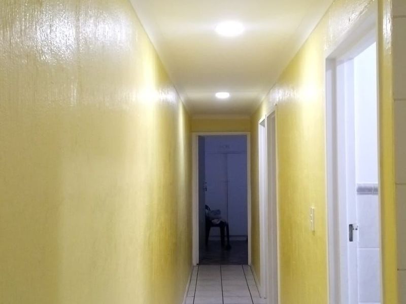 A bright hallway featuring tiled flooring and recessed downlights, providing access to multiple rooms within the home.