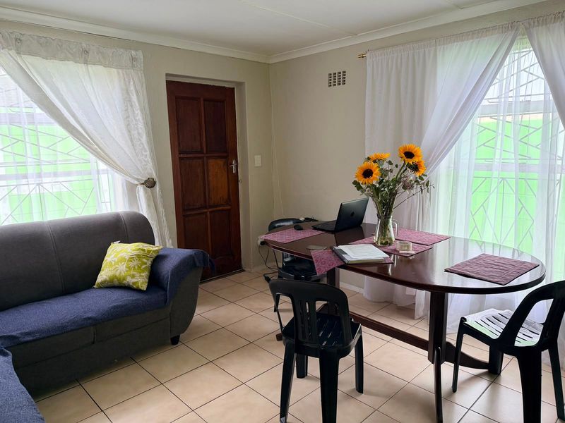 A functional living area featuring ceramic floor tiles, a timber door, and large windows fitted with security bars.