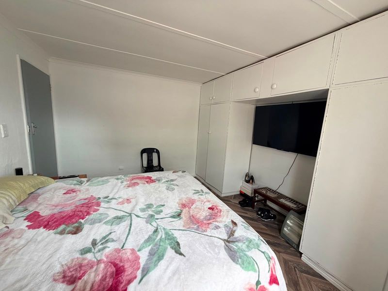 A bedroom featuring built-in cupboards with overhead storage and herringbone pattern flooring.