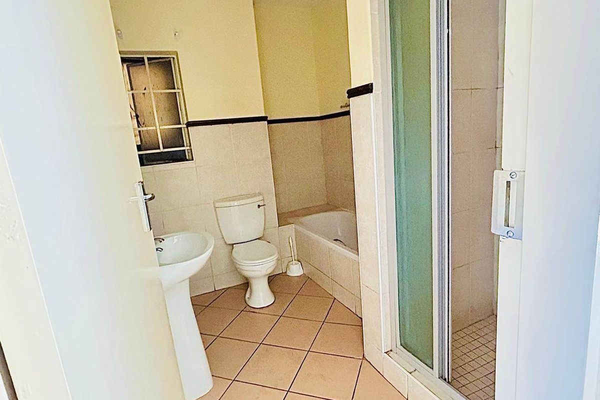 A functional bathroom featuring a pedestal basin, toilet, bathtub, and a separate shower enclosure with tiled finishes throughout.