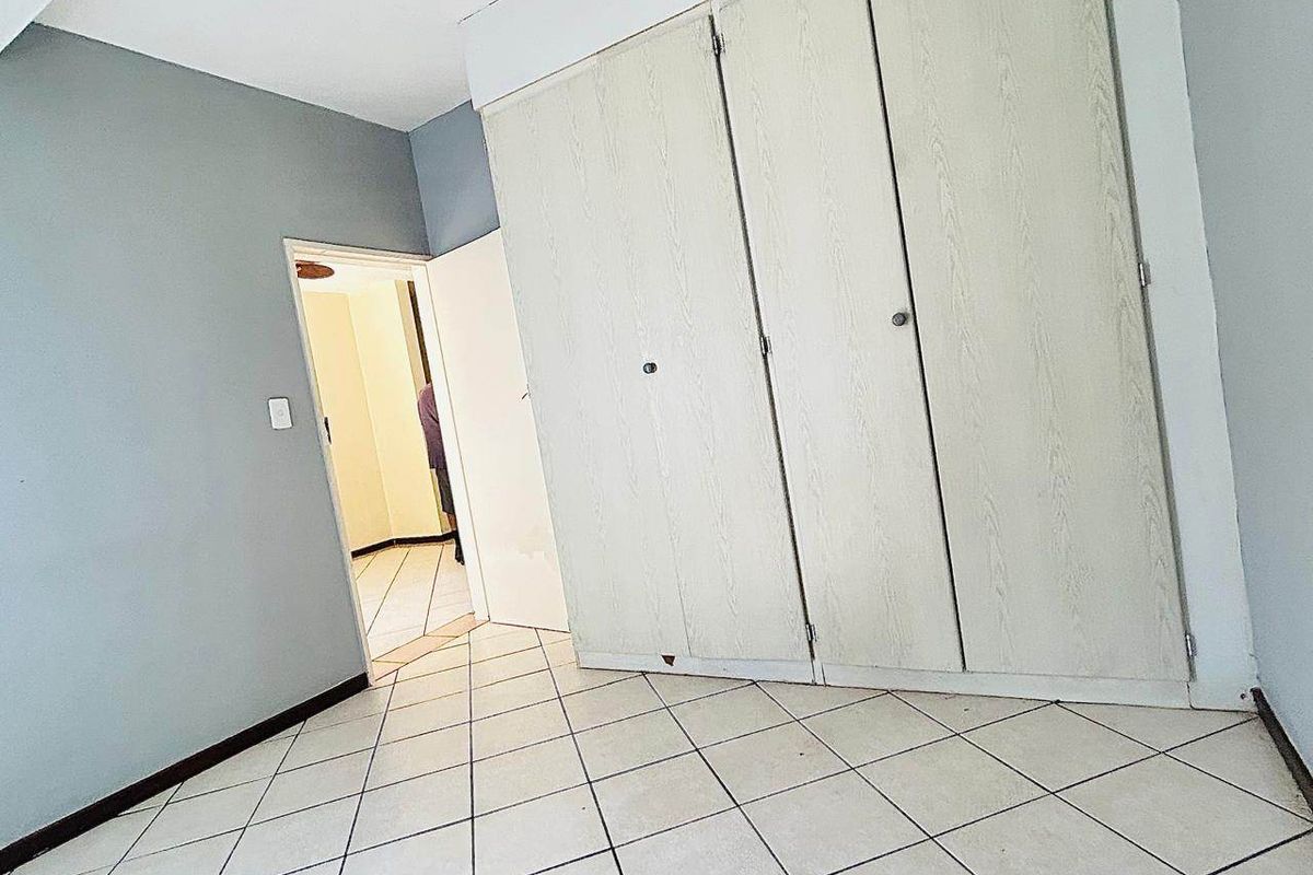 An empty bedroom featuring built-in cupboards and tiled flooring, offering a neutral canvas for personalization.