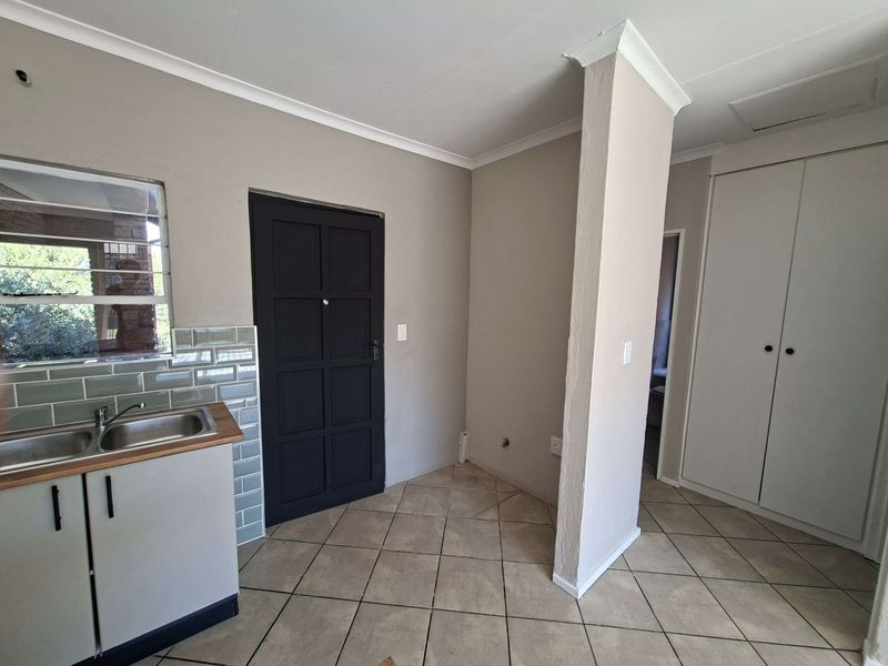 A functional kitchen area featuring a stainless steel sink, subway tile backsplash, tiled flooring, and built-in storage cupboards.
