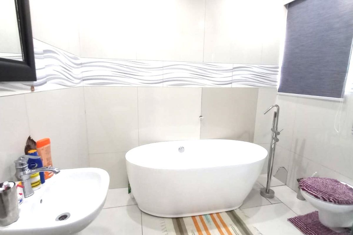 Modern bathroom featuring a sleek freestanding bathtub, wall-mounted basin, and wall-hung toilet with contemporary tiled finishes.