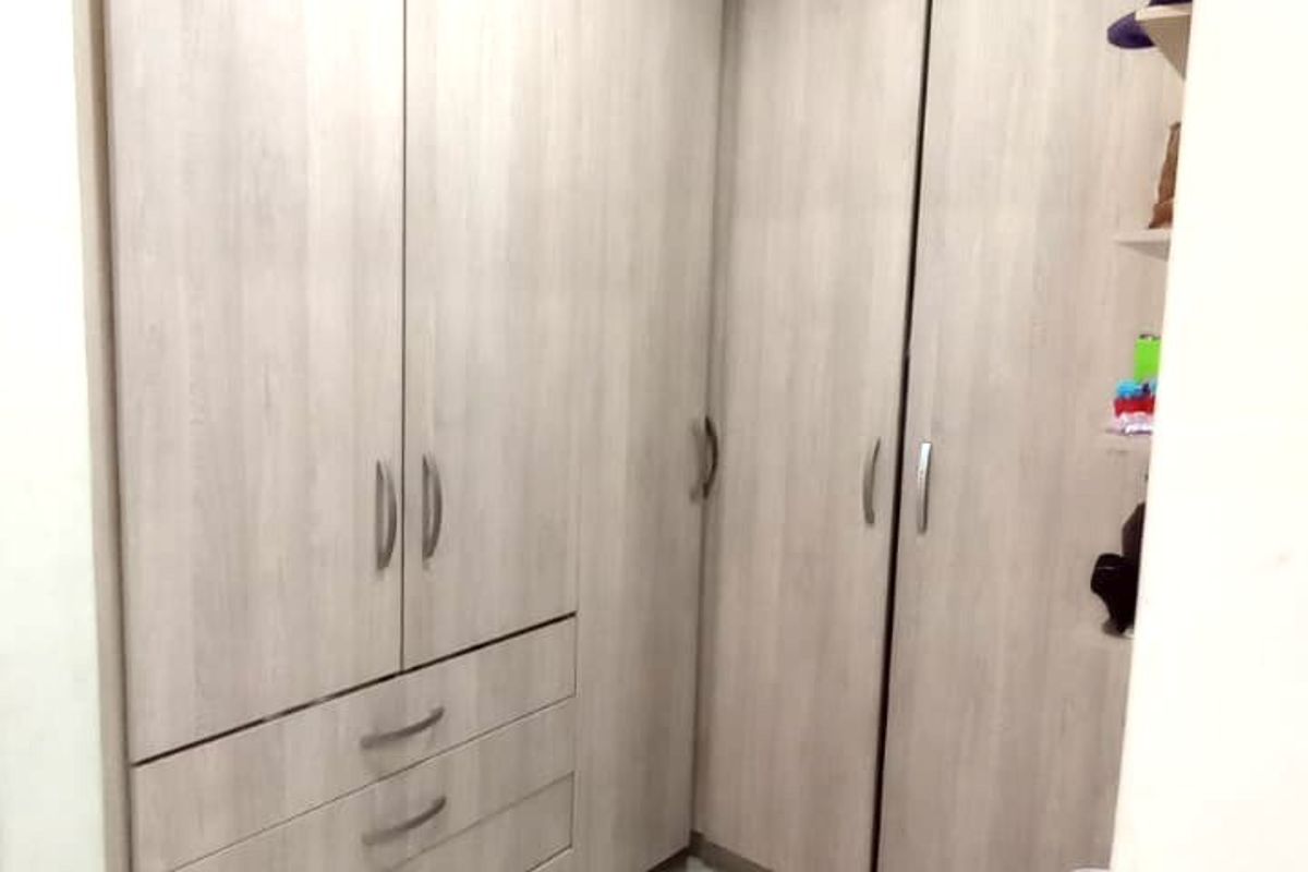 A clean and functional walk-in closet or dressing area featuring modern light wood-grain built-in cabinetry and neutral tiled flooring.
