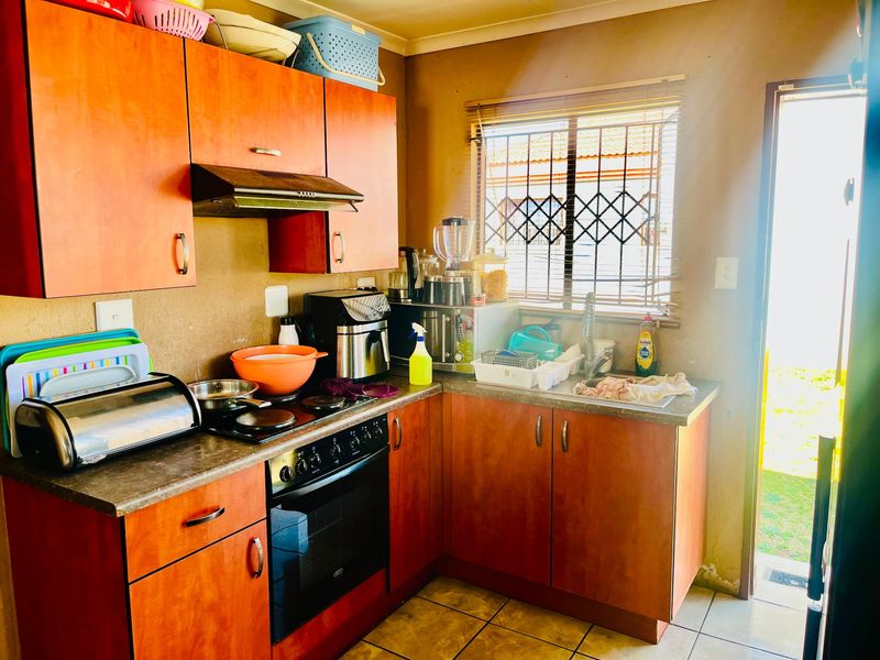 A functional kitchen featuring wood-tone cabinetry, built-in oven and hob, and direct access to the exterior through a side door.