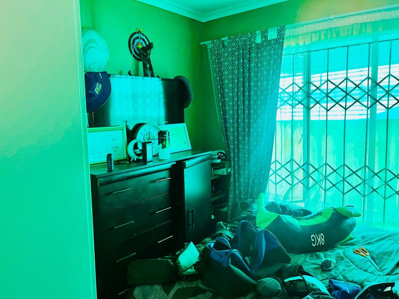 A bedroom featuring a window with a fitted security gate and curtain tracks, currently used as a personal living space.