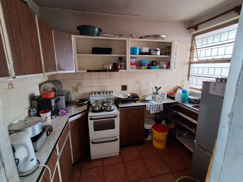 A compact kitchen featuring dated cabinetry, a tiled backsplash, and a freestanding stove, offering significant potential for modernization and renovation.