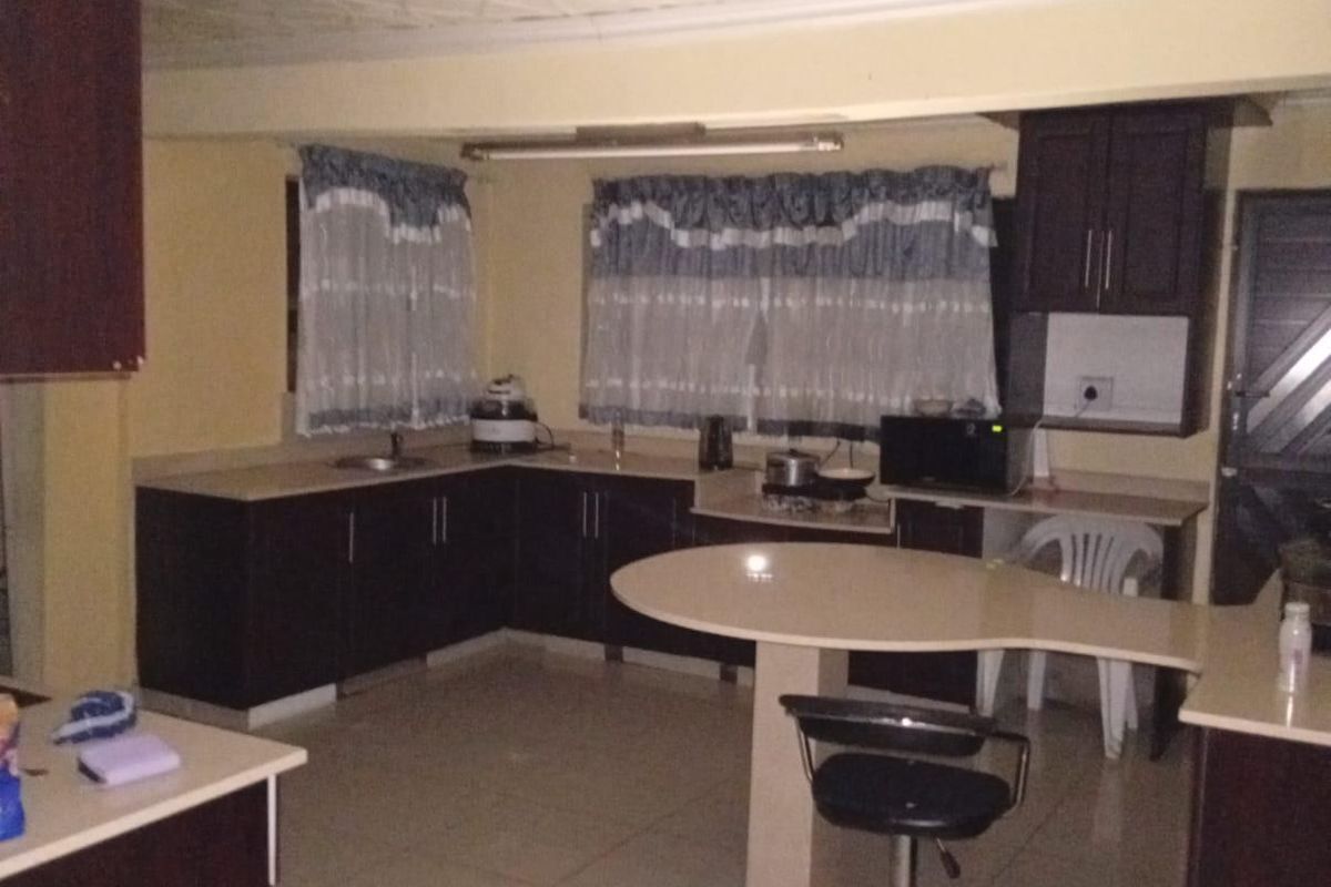 A kitchen featuring dark cabinetry, tiled flooring, and a breakfast bar, currently requiring ceiling repairs and general maintenance.