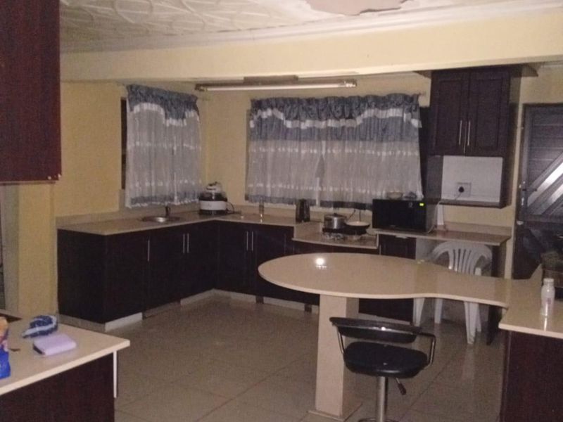 A kitchen featuring dark cabinetry, tiled flooring, and a breakfast bar, currently requiring ceiling repairs and general maintenance.