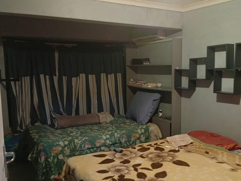 A bedroom featuring tiled flooring, built-in shelving units, and a ceiling with visible structural cracking.