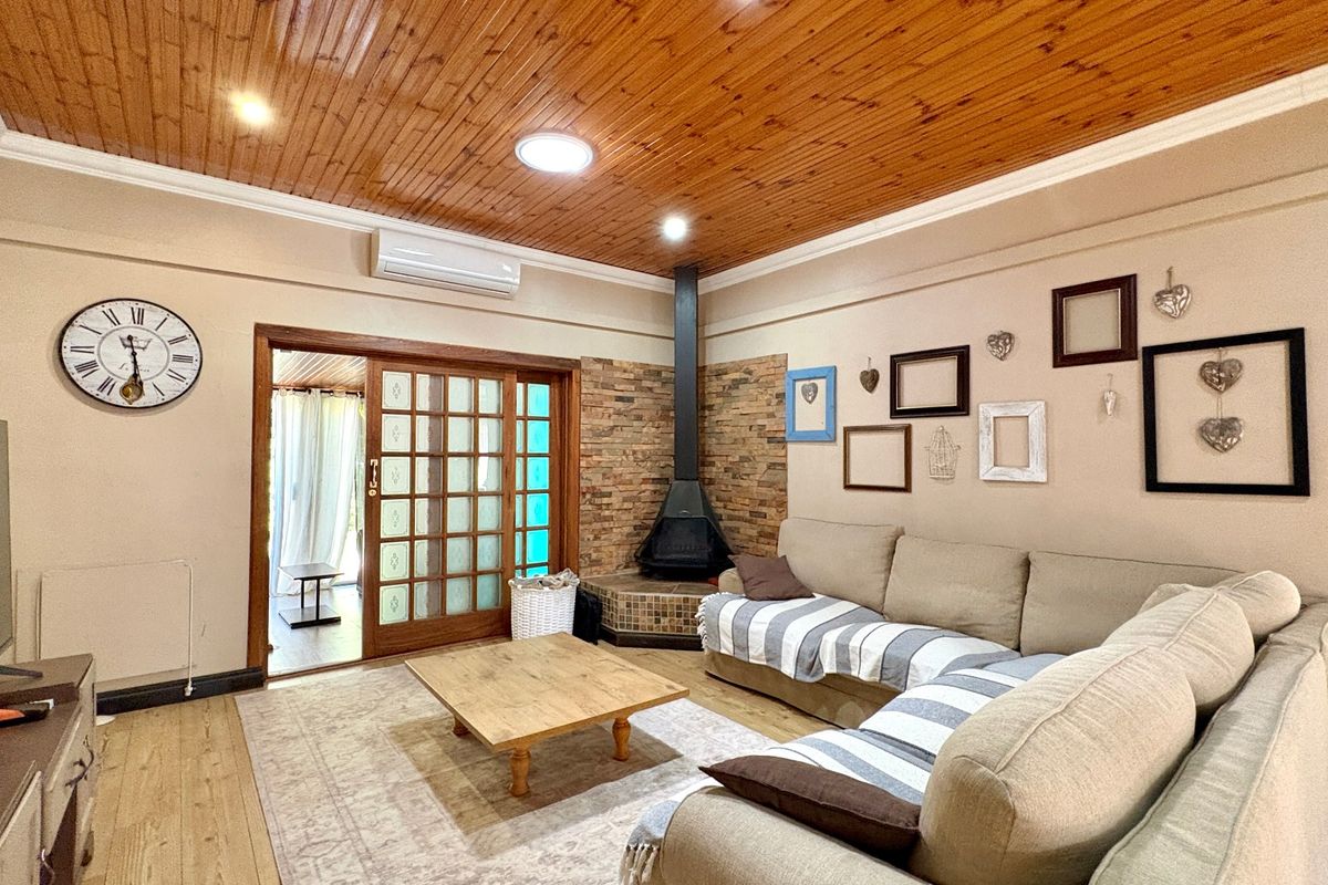 Spacious living room featuring a timber-clad ceiling, stone feature wall with a fireplace, and direct access to an outdoor area via sliding doors.