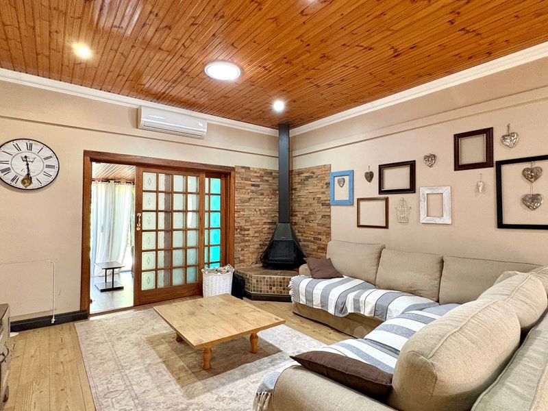 Spacious living room featuring a timber-clad ceiling, stone feature wall with a fireplace, and direct access to an outdoor area via sliding doors.
