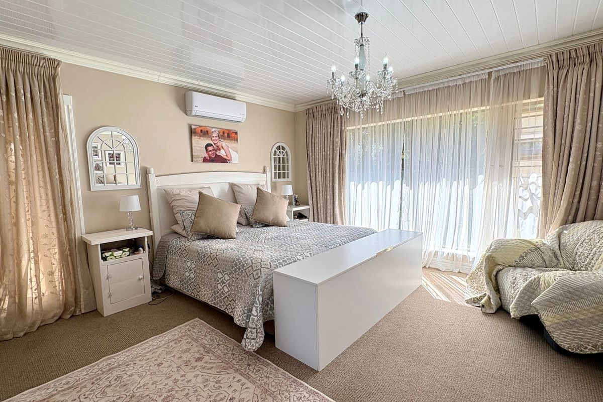 A well-maintained bedroom featuring a tongue and groove ceiling, a central chandelier, and large sliding glass doors providing natural light.
