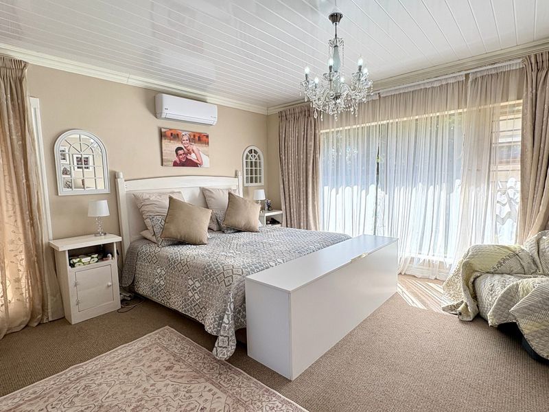 A well-maintained bedroom featuring a tongue and groove ceiling, a central chandelier, and large sliding glass doors providing natural light.