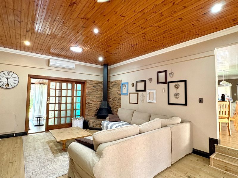 Spacious living room featuring a warm wood-paneled ceiling, a stone-clad fireplace, and direct access to an outdoor area through sliding glass doors.