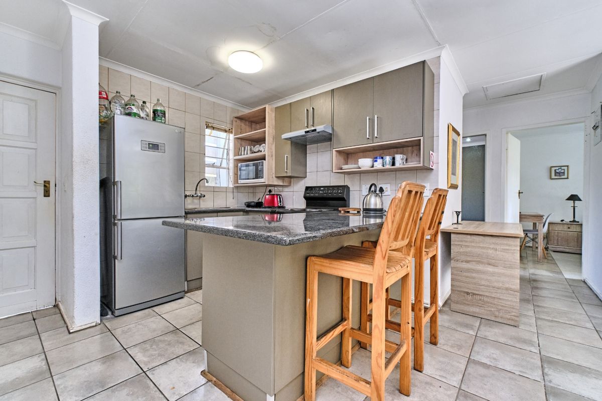 A functional kitchen featuring granite countertops, built-in cabinetry, and a breakfast bar, with tiled flooring and backsplash throughout.