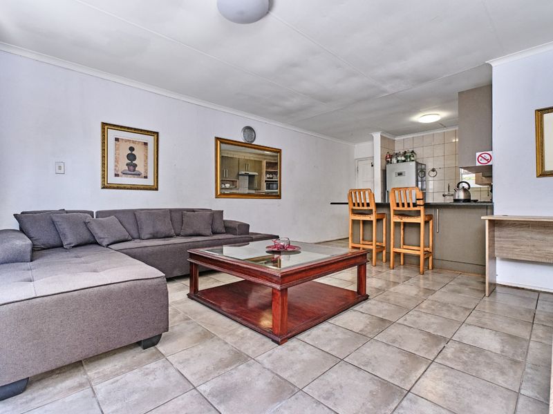 Open plan living area featuring tiled flooring and a functional kitchen with a breakfast bar, providing a versatile space for dining and relaxation.