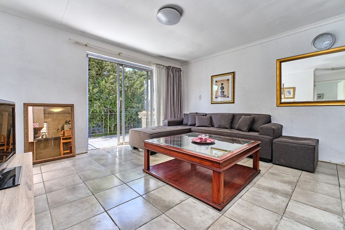 A bright living room featuring tiled flooring and a sliding glass door providing access to an outdoor balcony area.