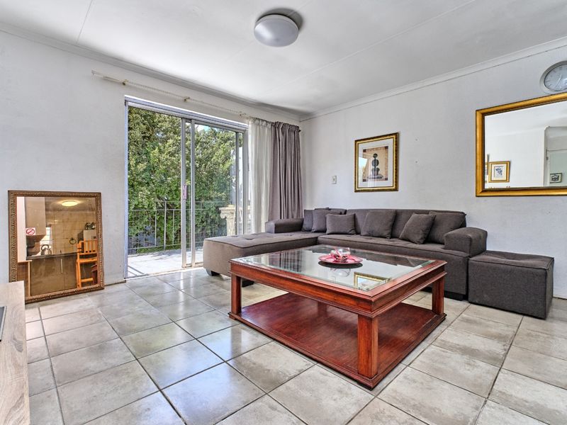 A bright living room featuring tiled flooring and a sliding glass door providing access to an outdoor balcony area.