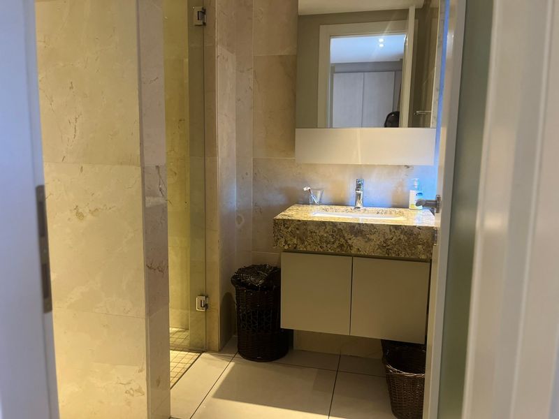 Modern bathroom featuring stone wall tiling, a floating vanity with a stone countertop, and a glass-enclosed shower area.