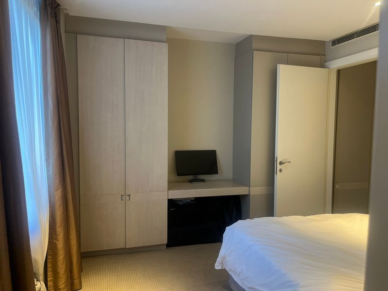 A well-maintained bedroom featuring built-in cabinetry, a dedicated desk area, carpeted flooring, and integrated air conditioning ventilation.