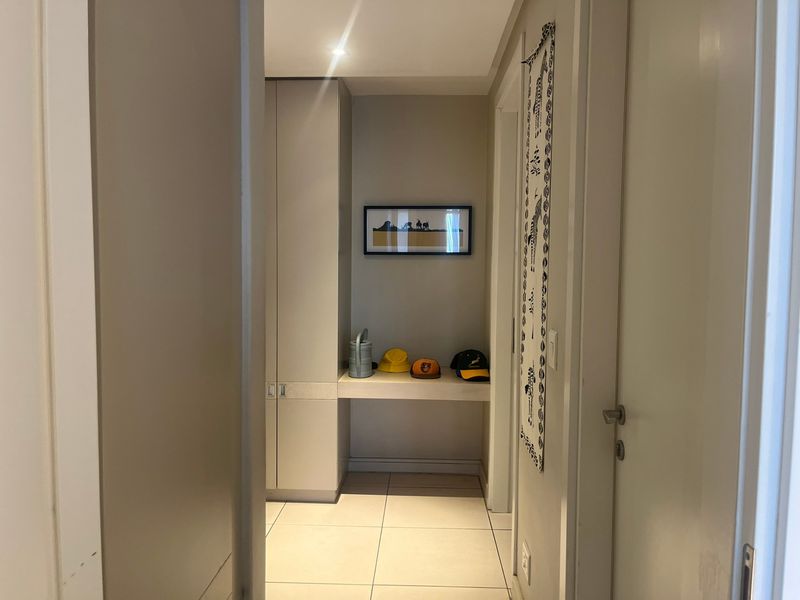 A clean, well-lit hallway featuring neutral tiled flooring and integrated built-in cabinetry for storage.