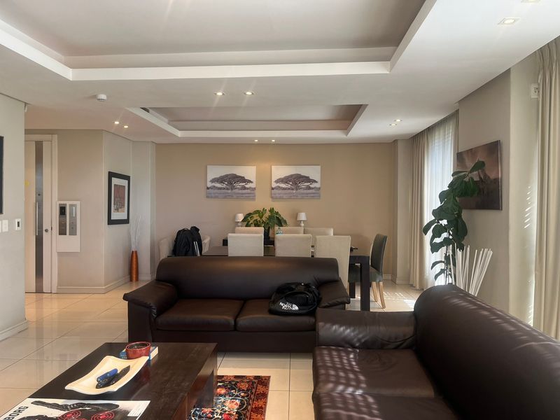 Spacious open-plan living and dining area featuring neutral walls, recessed ceiling lighting, and polished tiled flooring throughout.