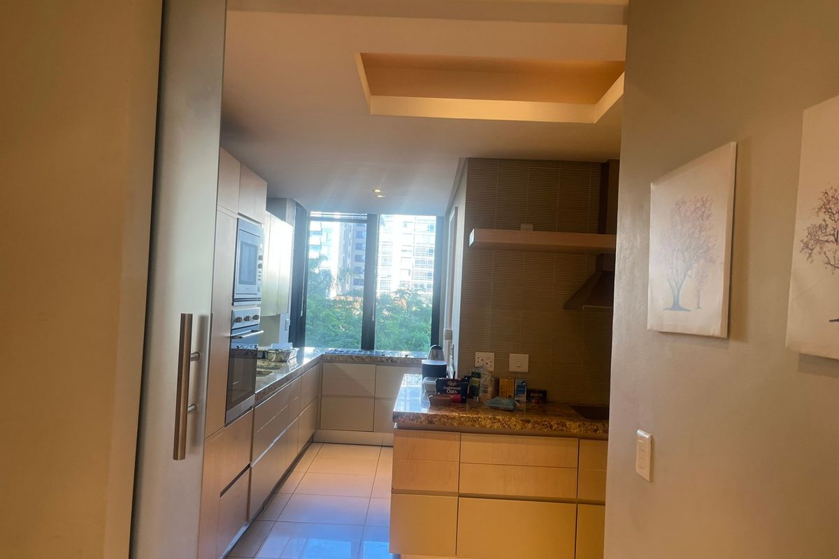 Modern kitchen featuring light wood cabinetry, granite countertops, integrated appliances, and tiled flooring with natural light from a large window.