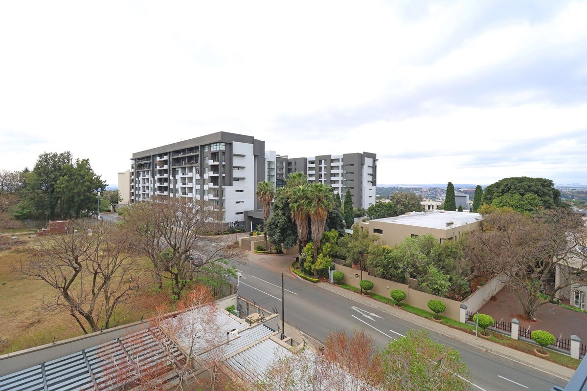 An elevated aerial view of the surrounding neighbourhood, featuring local apartment complexes, paved roads, and established landscaping.