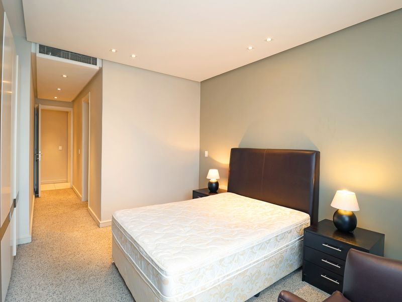 A well-maintained bedroom featuring neutral walls, recessed lighting, ducted air conditioning, and built-in cabinetry with carpeted flooring.