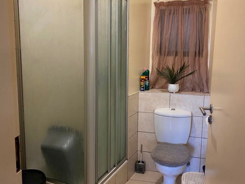 Compact bathroom featuring a shower enclosure, toilet, and extractor fan with tiled flooring and wall finishes.
