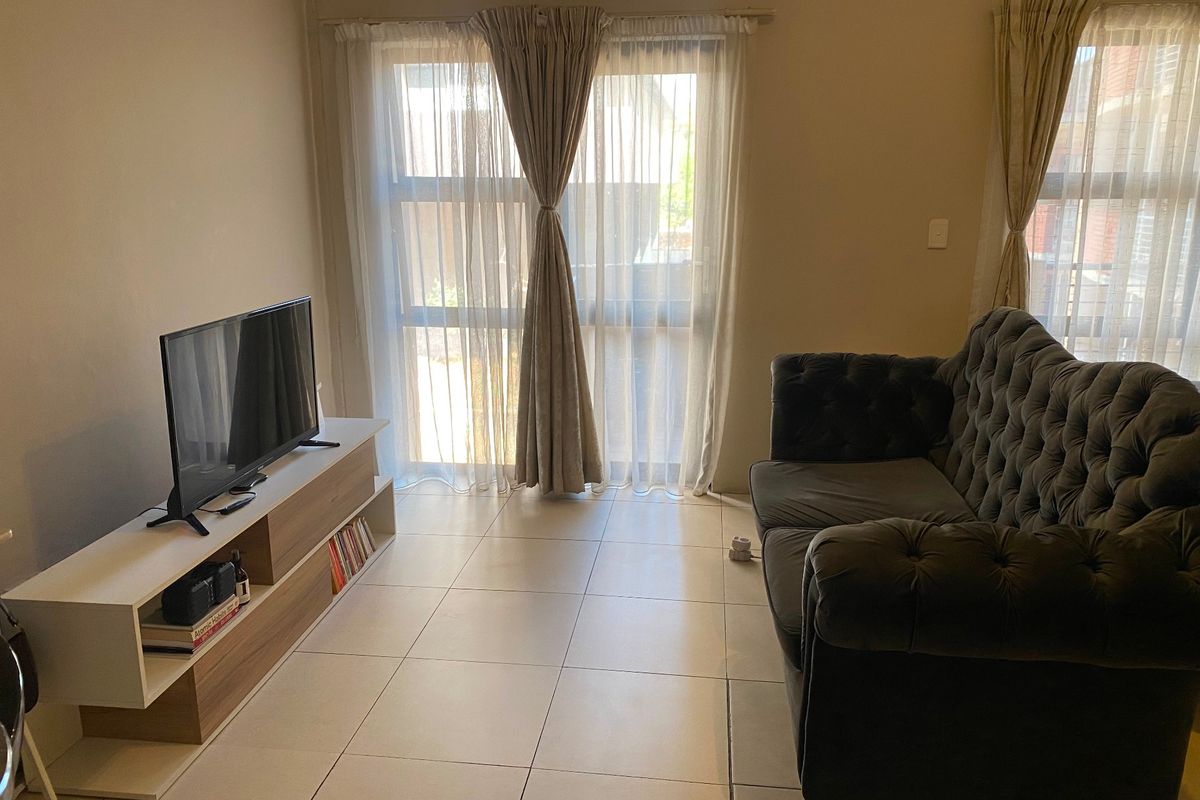 A living room featuring tiled flooring and large sliding glass doors that provide natural light.