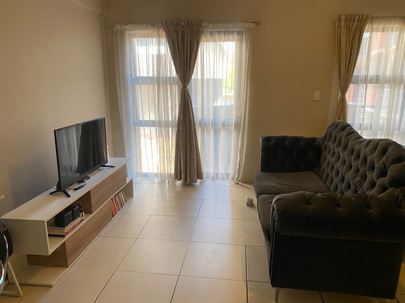A living room featuring tiled flooring and large sliding glass doors that provide natural light.