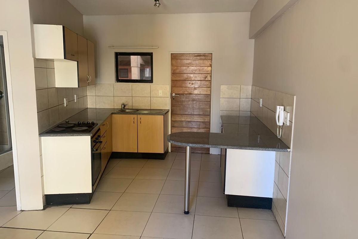 A functional kitchen featuring built-in cabinetry, granite countertops, a breakfast bar, and integrated cooking appliances, finished with tiled flooring and a tiled backsplash.