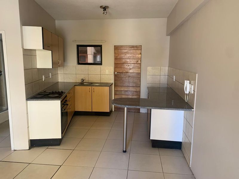 A functional kitchen featuring built-in cabinetry, granite countertops, a breakfast bar, and integrated cooking appliances, finished with tiled flooring and a tiled backsplash.