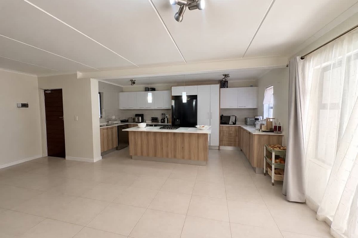 Spacious open-plan kitchen featuring a central island, modern cabinetry, and tiled flooring, seamlessly integrated with the living area.