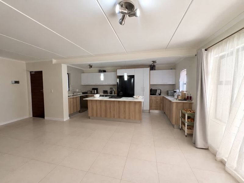 Spacious open-plan kitchen featuring a central island, modern cabinetry, and tiled flooring, seamlessly integrated with the living area.