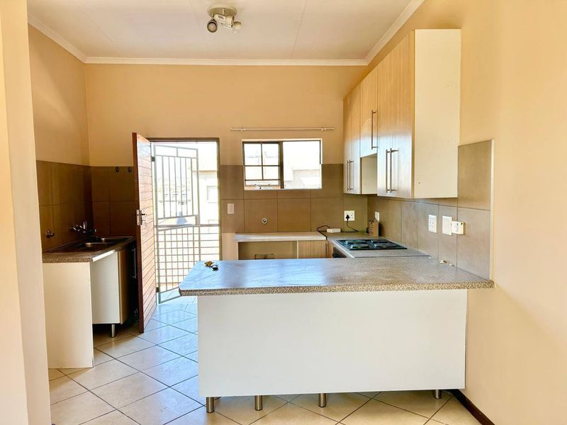 A functional kitchen featuring built-in cabinetry, a hob, and a double sink, with direct access to an exterior security gate.