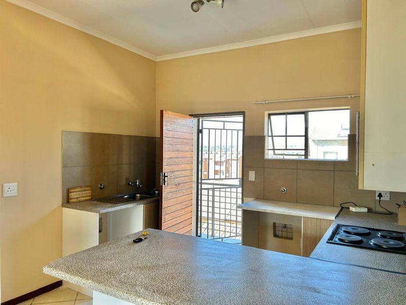 Functional kitchen featuring built-in cabinetry, laminate countertops, a built-in hob, and tiled backsplash, with direct access to an exterior balcony.