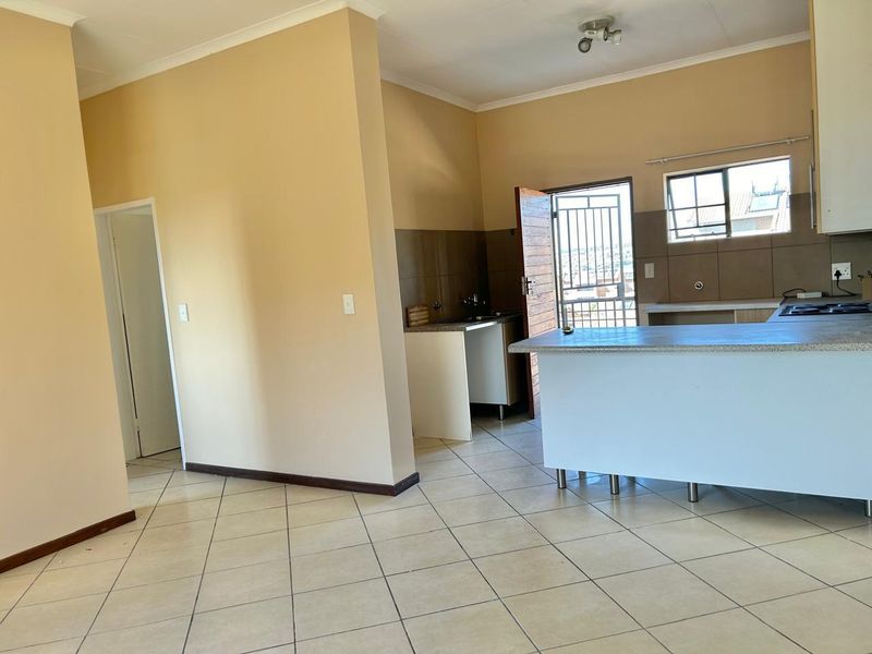 Open-plan kitchen and living area featuring tiled flooring, a central kitchen island, and direct access to an exterior security gate.
