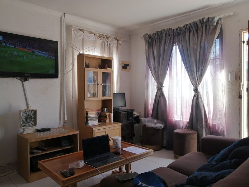 A functional living room featuring tiled flooring and wall-mounted television setup, offering a comfortable space for relaxation and entertainment.