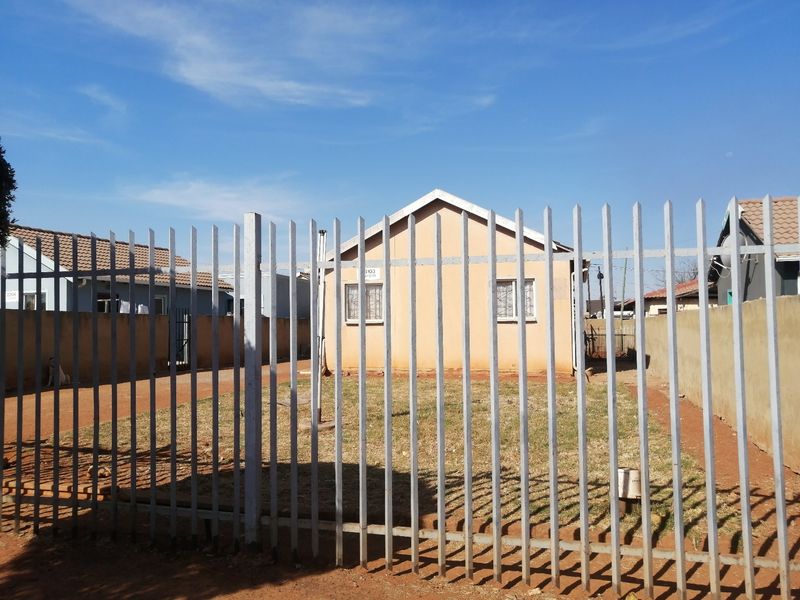 Front view of a detached house featuring a tiled roof, security bars on windows, and enclosed by steel palisade fencing.