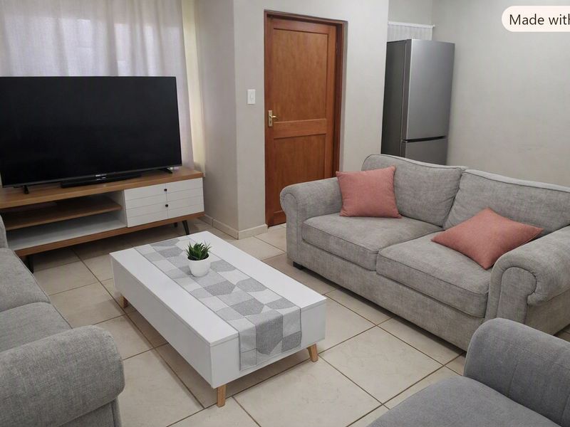 A comfortable living room featuring neutral tiled flooring and a solid wood door, providing a clean and functional space for relaxation.