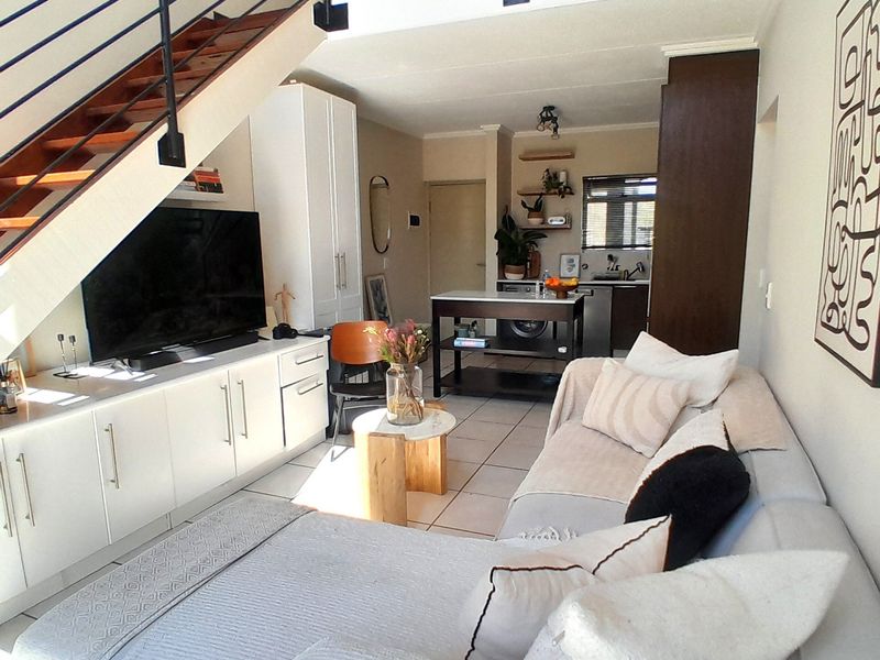 Open-plan living area featuring a modern staircase, built-in cabinetry, and a functional kitchen island, creating a cohesive and well-utilized living space.