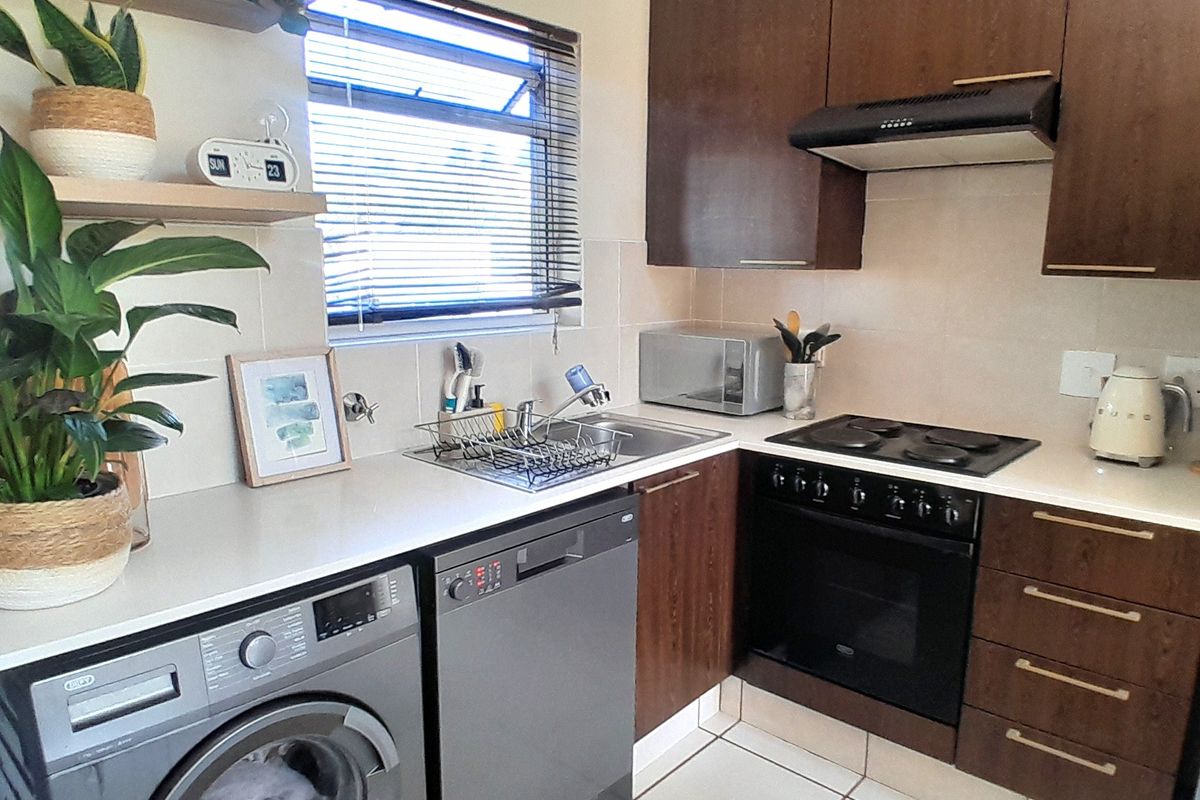 A functional kitchen featuring dark wood cabinetry, built-in oven with hob, extractor fan, and tiled flooring, offering a practical and well-maintained workspace.