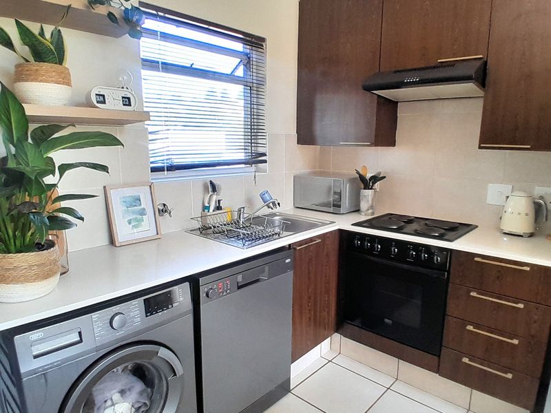 A functional kitchen featuring dark wood cabinetry, built-in oven with hob, extractor fan, and tiled flooring, offering a practical and well-maintained workspace.