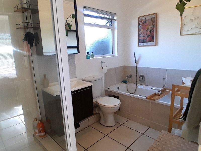 A functional bathroom featuring a separate shower enclosure, bathtub, vanity basin, and toilet with neutral tiled finishes.