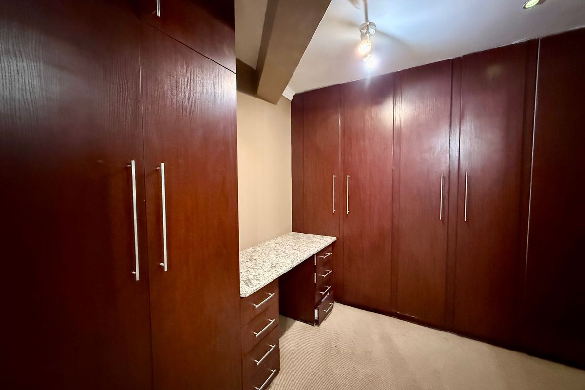 A bedroom featuring extensive dark wood built-in cabinetry and a integrated desk with a granite countertop, providing ample storage and workspace.