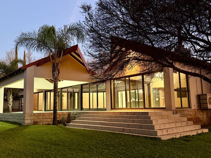 Rear view of the property featuring a spacious tiled patio, large sliding glass doors, and stone-clad steps leading to a well-maintained garden.